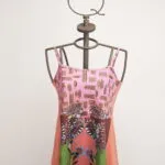 Sleeveless summer dress with floral print and geometric patterns, displayed on an artistic mannequin. Vibrant and colorful design ideal for the warm season. 