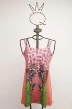 Sleeveless summer dress with floral print and geometric patterns, displayed on an artistic mannequin. Vibrant and colorful design ideal for the warm season.