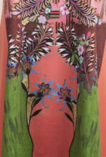 Motif floral vivant sur tissu, avec des feuilles et des fleurs colorées sur un fond rose et vert. Parfait pour les vêtements d'été et les accessoires de mode.