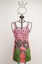 Colorful summer dress with floral and geometric patterns, displayed on a stylish mannequin. Lively design with pink and green hues, ideal for casual occasions.