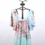 Summer dress with bell sleeves, presented on a mannequin. The dress features a floral design in shades of blue and pink on a light blue background, ideal for casual occasions and summer days. 