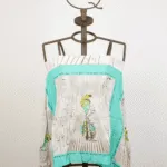 Top en tissu léger avec impression de plumes colorées, présenté sur un mannequin. Un modèle idéal pour l'été, pour des tenues décontractées et cool. 