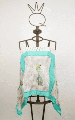 Top in tessuto leggero con stampa colorata di piume, esposto su un manichino. Design estivo ideale per outfit casual e freschi.