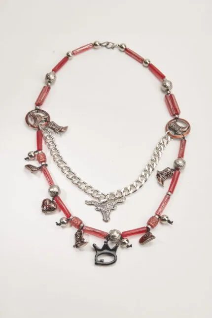 Collana artistica con perline rosse e pendenti metallici, tra cui stivali, cuori e un simbolo di toro, perfetta per un look originale e creativo.