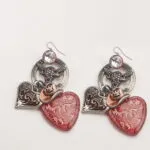 Orecchini pendenti a forma di cuore rosso, decorati con elementi metallici e cristalli, perfetti per un look elegante e originale. Ideali per occasioni speciali o come accessorio quotidiano.