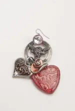 Orecchino decorativo con ciondoli a forma di cuore, uno rosso traslucido e uno con design ornamentale, insieme a un elemento metallico con teschio e cristallo. Ideale per uno stile bohemien e originale.