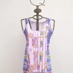Abito estivo colorato su manichino, caratterizzato da un mix di fantasie vivaci in tonalità di rosa, blu e giallo. Ideale per occasioni casual e giornate calde.