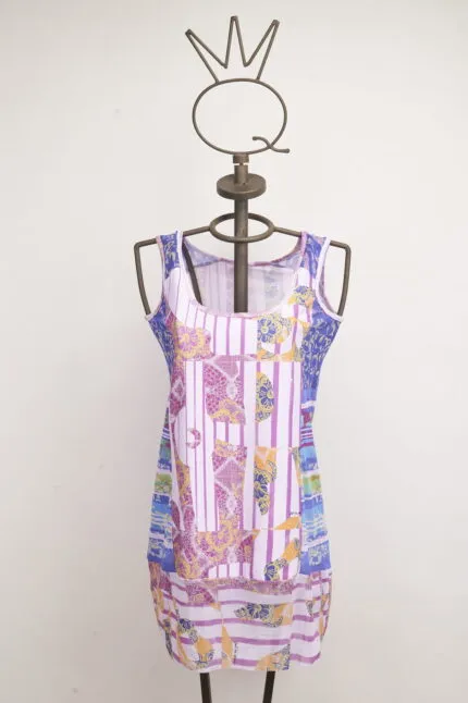 Abito estivo colorato su manichino, caratterizzato da un mix di fantasie vivaci in tonalità di rosa, blu e giallo. Ideale per occasioni casual e giornate calde.