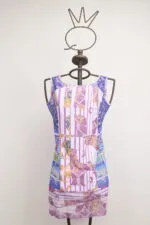 Abito estivo colorato in tonalità di viola e rosa, con un design a motivi geometrici e floreali, esposto su un manichino con testa a forma di corona.