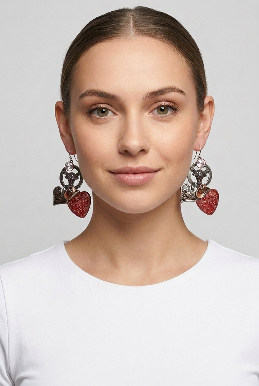 15SSNS945_model Orecchini a forma di cuore rossi e argento indossati da una donna, con un top bianco, su sfondo grigio chiaro. Accessorio di moda che aggiunge un tocco elegante e moderno al look.