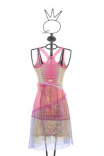 Vestito in maglia jacquard e tulle, caratterizzato da una vivace stampa a fiori, esposto su un manichino. Il design presenta spalline incrociate e un mix di tessuti trasparenti e colorati.