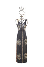 Vestito a fantasia lungo, con dettagli decorativi in tessuto leggero e trasparente, presentato su un manichino artistico. Design elegante e moderno, ideale per occasioni speciali.
