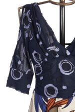 Top di un vestito a fantasia con maniche a sbuffo, caratterizzato da un design navy con motivi circolari in tonalità chiare. Ideale per occasioni eleganti o casual.