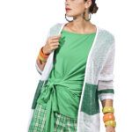 Donna elegante che indossa un cardigan bianco e verde, abbinato a una maglietta verde e pantaloni a quadri. Accessori colorati completano il look moderno e fresco. 