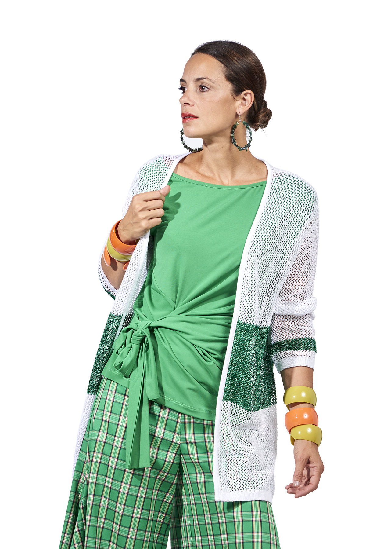 20SSQ3030_04_a1 Donna elegante che indossa un cardigan bianco e verde, abbinato a una maglietta verde e pantaloni a quadri. Accessori colorati completano il look moderno e fresco.