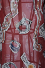 Vestito corto a fantasia con motivo colorato su fondo rosso, caratterizzato da disegni di anelli e forme geometriche, ideale per un look estivo e vivace.