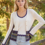Modello di twin set in cotone a costine composto da canotta bianca e cardigan con dettagli colorati, indossato da una giovane donna, in un ambiente naturale.